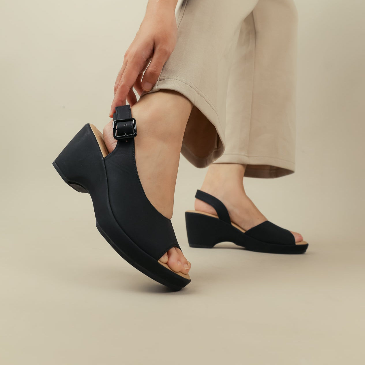 Black sandals worn by a person on a beige background