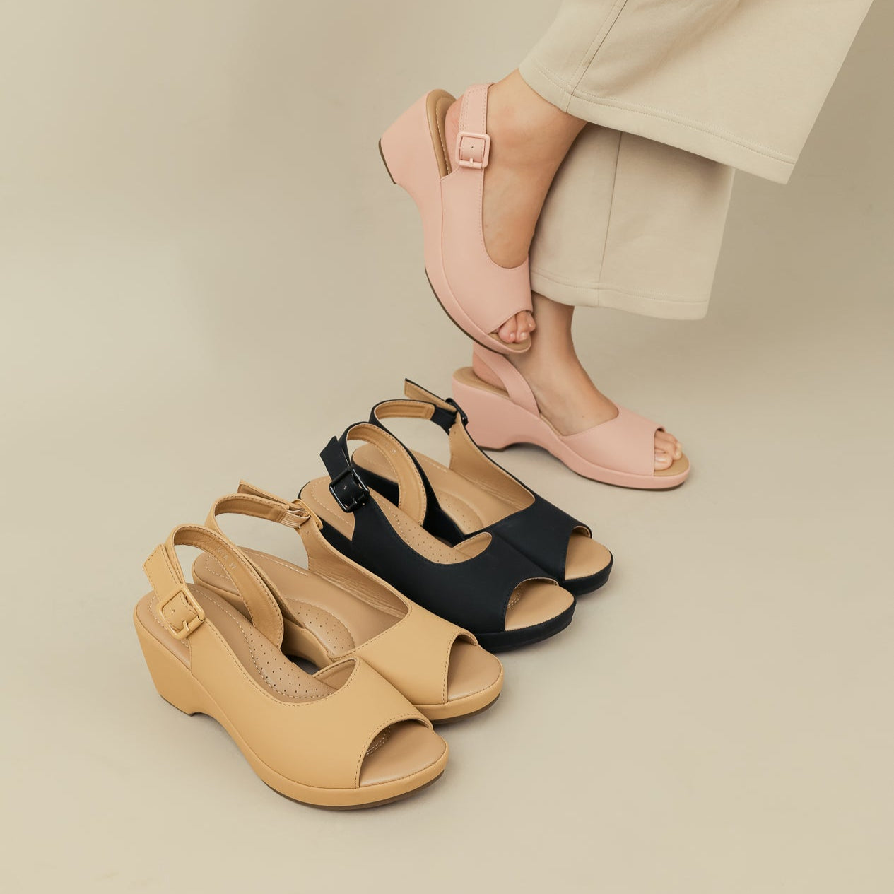 Three pairs of sandals in beige, black, and pink on a neutral background